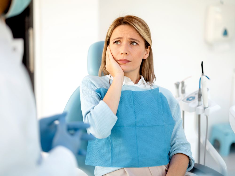 Mulher em consulta odontológica avaliando sintomas relacionados à dor neuropática em implante dentário.